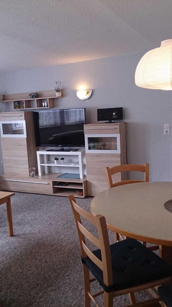 A compact living space with a TV, wooden furniture, and a lamp.