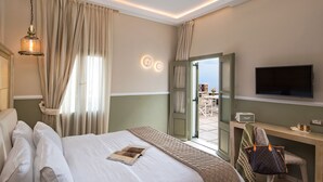 A hotel room with a bed, a desk, a television, and a view of the outside. - 2 Bed Villa - Sleeps 4 - Pool - Private Chef (Santorini)
