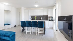 Una cocina moderna con armarios blancos, una isla central con taburetes de bar y un horno empotrado.