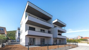Un edificio residencial moderno de varios pisos, con balcones, techo plano y cielo despejado.