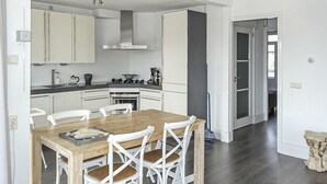 Een moderne keuken met witte kasten, een houten eettafel en witte stoelen.