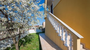 A building with a yellow exterior, a white balustrade, and a tree with white blossoms. - 1 bedroom beautiful apartment in Pula (Pula)