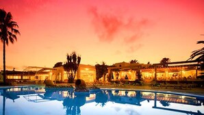 A swimming pool with a reflection of palm trees and buildings at dusk. - Cala Domingos Apartments (Manacor)