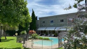 En boligbygning med swimmingpool, overdækket terrasse og en lukket baghave.