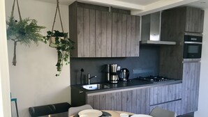 A modern kitchen with wooden cabinets, a gas stove, and a coffee maker.