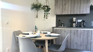 A modern kitchen with wooden cabinets, a dining table with chairs, and a hanging plant.