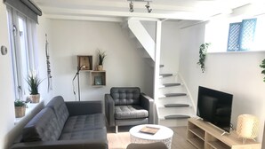 A modern living room with a sofa, armchair, coffee table, and TV.