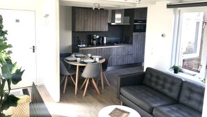 A modern kitchen with dark wooden cabinets, a central island, and a dining area with a round table and four chairs.