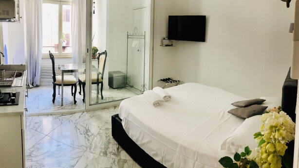 A hotel room with a bed, a TV, a desk with a chair, and a bathroom visible through an open door.