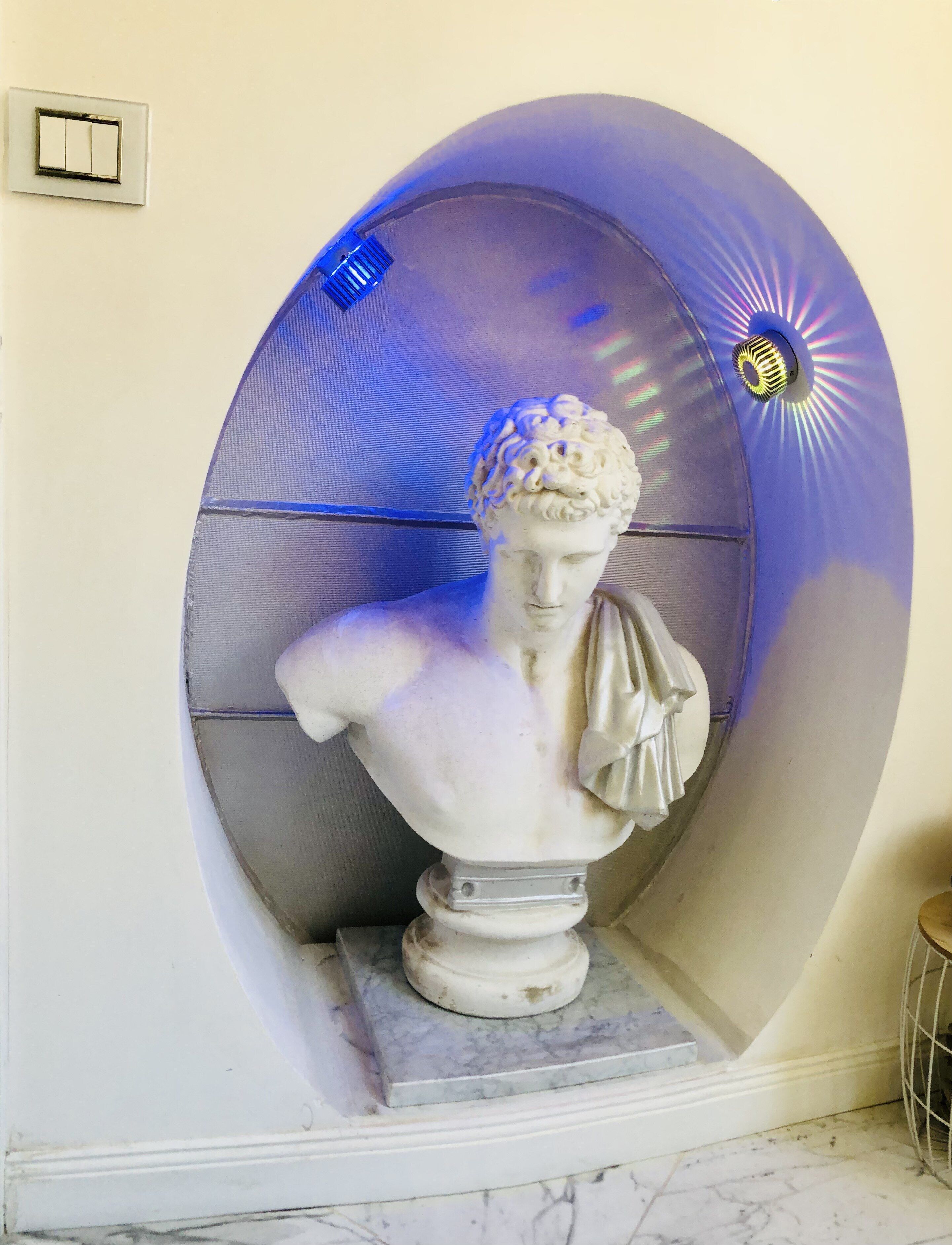 Een marmeren buste sculptuur in een nis, met een structuurrijke achtergrond en een spotlicht effect.