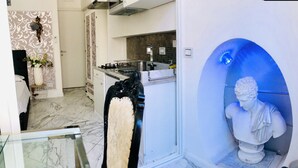 A modern kitchen with a marble floor, a white cabinet, and a blue accent wall with a statue.
