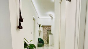 A hallway with marble flooring, a potted plant, and a green chair.