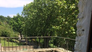 An outdoor area with a concrete floor, metal railing, and a stone wall. - Gîte de 4 Personnes Dans une Maison en Pierre de Pays (Matra)