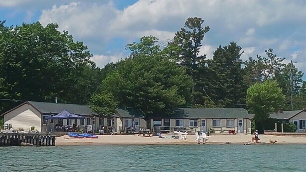 Un hôtel situé au bord de l’eau, composé de plusieurs bâtiments, avec une plage de sable et des bateaux.