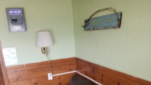 Une pièce avec un canapé en cuir marron, des lambris en bois, une lampe fixée au mur et un élément de décoration représentant un poisson.