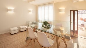 Un comedor moderno con una mesa de vidrio, sillas blancas y una planta en maceta.