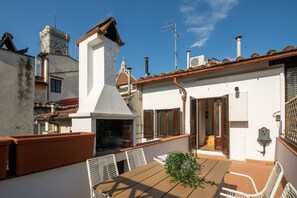 Enjoy dining or socializing on the rooftop terrace with a table and chairs, surrounded by a charming view.