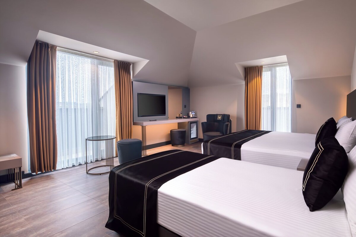 A hotel room with two beds, a TV, a desk, and a chair.