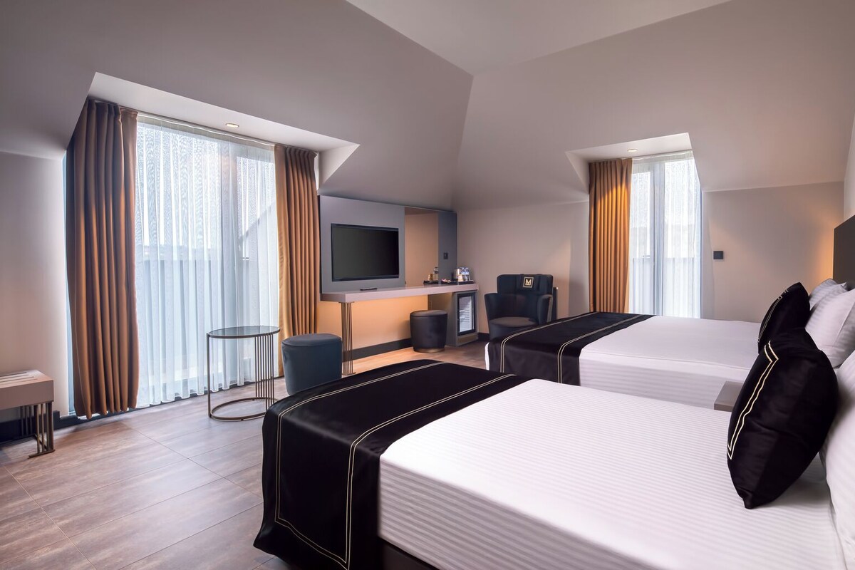A hotel room with two beds, a TV, a desk, and a chair.