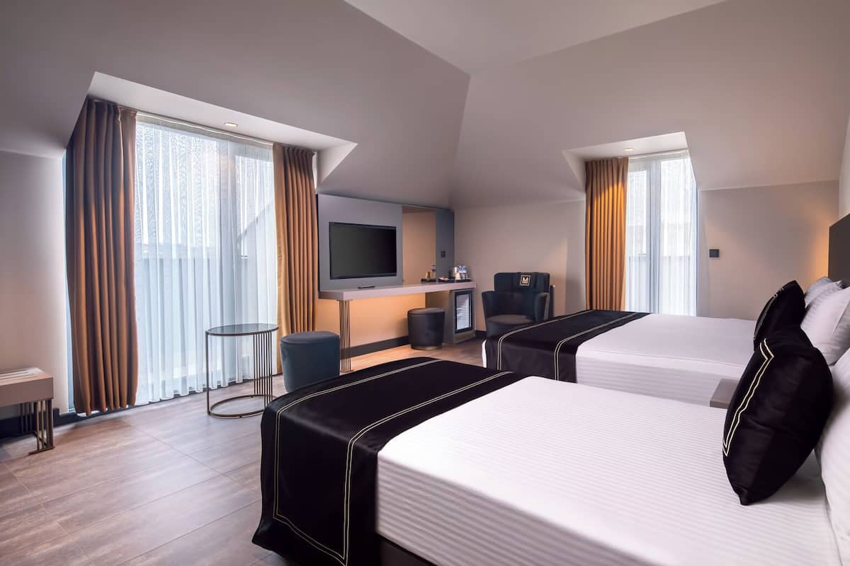 Habitación de hotel con dos camas, televisión, escritorio y una silla.