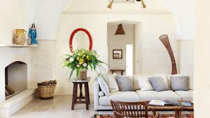 Una sala de estar acogedora con chimenea, un sofá, una mesa de centro y una silla de mimbre.