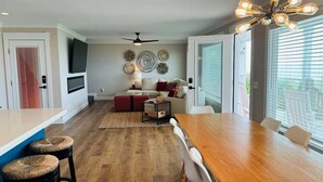A modern kitchen with a dining area, wooden flooring, and a ceiling fan. - Experience stunning oceanfront views at Nauti Time, a spacious 5-bedroom retreat in Holden Beach. (Holden Beach)