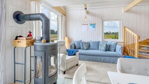 Ett mysigt vardagsrum med en modern öppen spis, en bekväm soffa och en trätrappa.