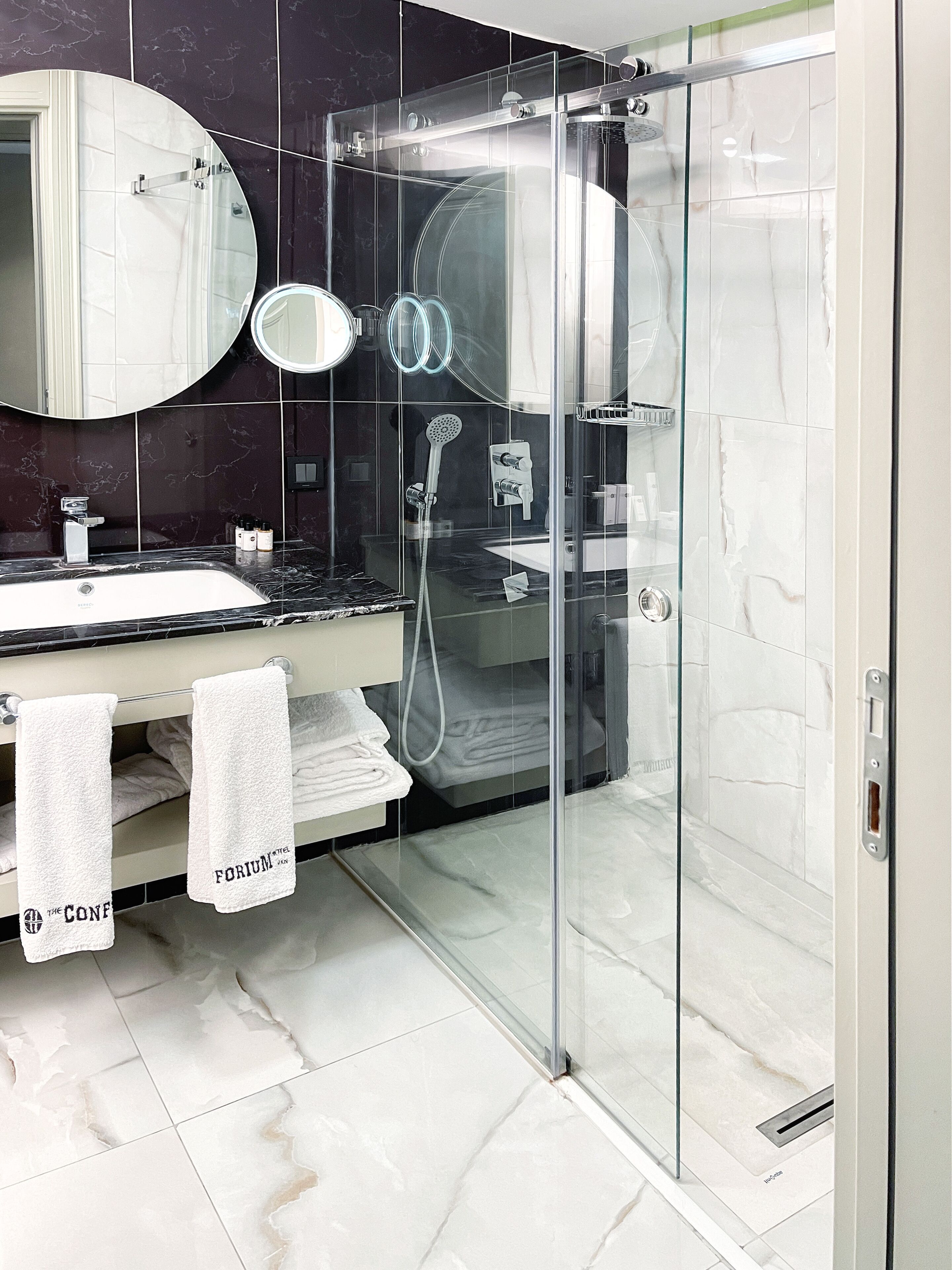 A modern bathroom with a glass-enclosed shower, a vanity with a sink, and two towels hanging on a rack.