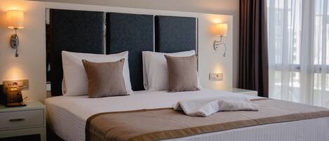 Una habitación de hotel con una cama grande, dos mesitas de noche y una lámpara.