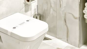 A bathroom with a toilet, a paper towel dispenser, and a towel rack.