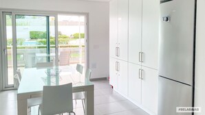 A modern kitchen with a glass dining table, white cabinets, and a refrigerator. - Modern, air-conditioned family apartment with pool. 10 minute walk to beach (Salir do Porto)