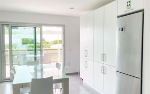 A modern kitchen with a glass dining table, white cabinets, and a refrigerator. - Modern, air-conditioned family apartment with pool. 10 minute walk to beach (Salir do Porto)