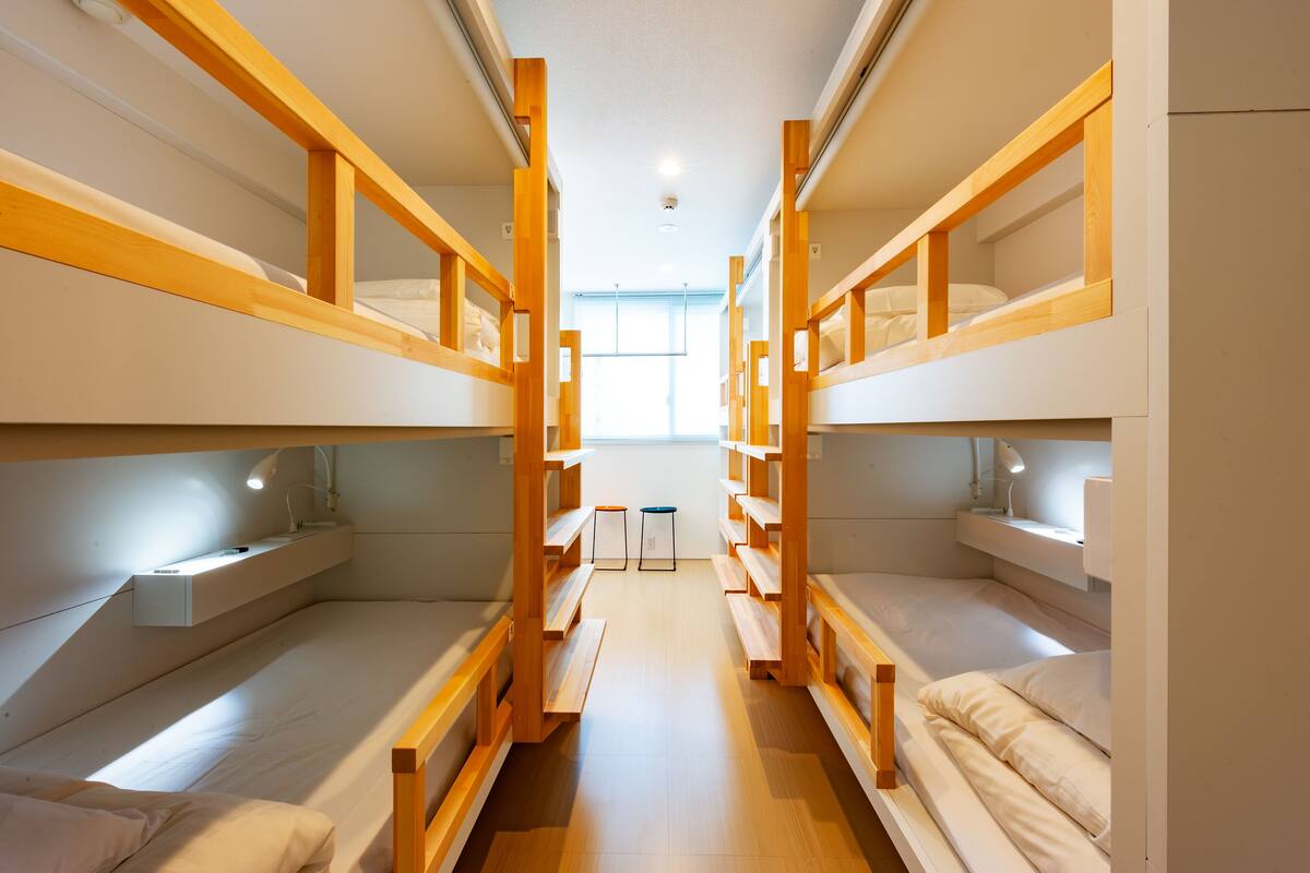 A bunk bed room with wooden frames, a desk, and a chair.