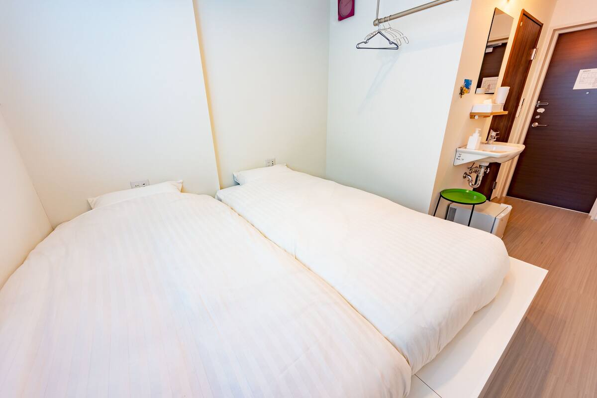 A small, clean room with a single bed, a small sink, and a mirror.