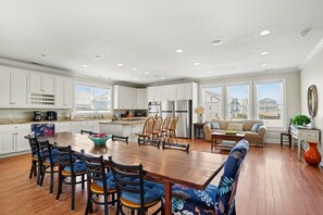A spacious kitchen with white cabinets, a dining area with a wooden table and chairs, and a living room with a sofa and a coffee table.