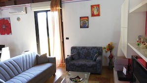 A living room with a sofa, a coffee table, and a television. - Casa Benty - Entire Loft (Palermo)
