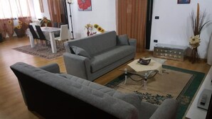 A living room with a grey sofa, a coffee table, and a dining area with a table and chairs. - Casa Benty - Entire Loft (Palermo)