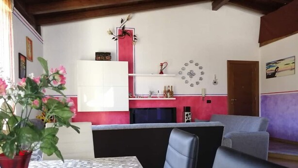 A dining area with a checkered table, a red vase with flowers, and a modern kitchen in the background. - Casa Benty - Entire Loft (Palermo)