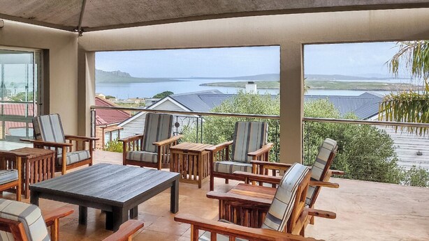 A balcony with wooden furniture and a view of a lake. - Casa de Palmera, Langebaan 6-sleeper (Langebaan)
