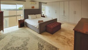 A bedroom with a large bed, a nightstand, a dresser, a wardrobe, and a balcony with a view. - Casa de Palmera, Langebaan 6-sleeper (Langebaan)