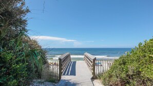 A wooden boardwalk leading to a beach with a clear view of the ocean.