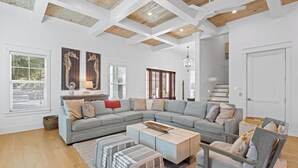 A spacious living room with a large L-shaped sectional sofa, a coffee table, and a wooden accent wall.