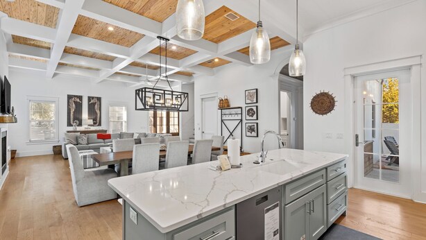 A spacious kitchen with a large island, modern pendant lights, and a view to the outside.
