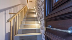 A wooden staircase with a stone wall on one side and a wooden door at the bottom. - Guarda Il Porto Apartment - Hydra port (Idra)