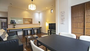 A modern living room with a dining area, wooden accents, and a large TV.