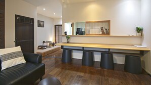 A modern living room with a dark leather sofa, a wooden bench, and a long wooden table with stools.