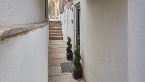 A narrow alleyway with a welcome mat, a door, and a staircase leading to a building. - The Garden Apartment (Harrogate)