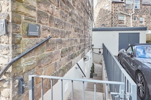 A stone wall with a number 7 sign, a metal gate, and a parked car. - The Garden Apartment (Harrogate)