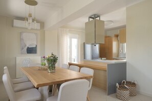 Een moderne keuken met een centraal eiland, witte stoelen en een eettafel met een bloemenvaas.