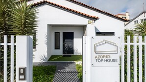 Une maison moderne avec un toit en tuiles, une porte noire et une enseigne sur laquelle on peut lire : « AZORES TOP HOUSE ».